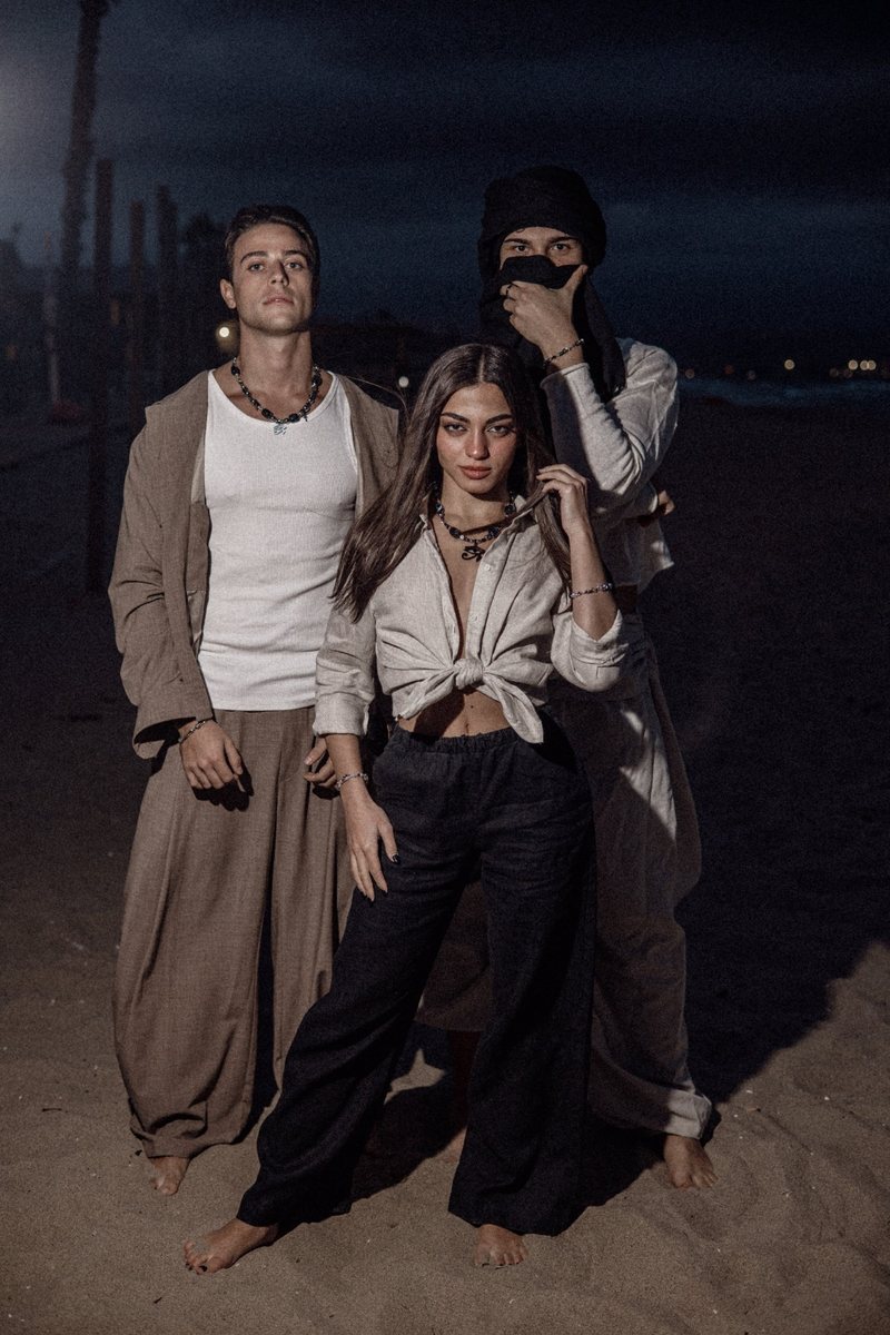 Tre ragazzi di notte sulla spiaggia, in lino e a piedi nudi, con le collane di THE EYE ARCHIVE 001